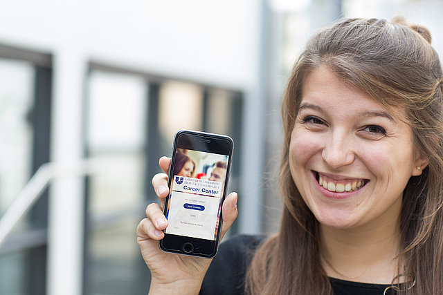 Frau zeigt Career Center App auf Smartphone