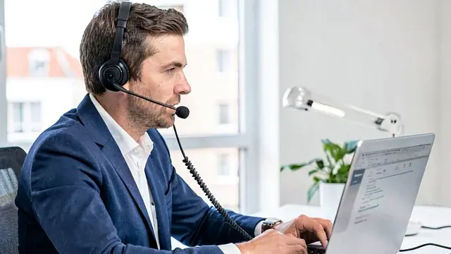 Mann mit Headset vor Notebook