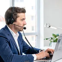 Mann mit Headset vor Notebook