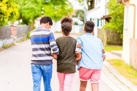 drei ca. 13 jährige Jungen mit Migrationshintergrun, laufend mit dem Rücken zum Betrachter 