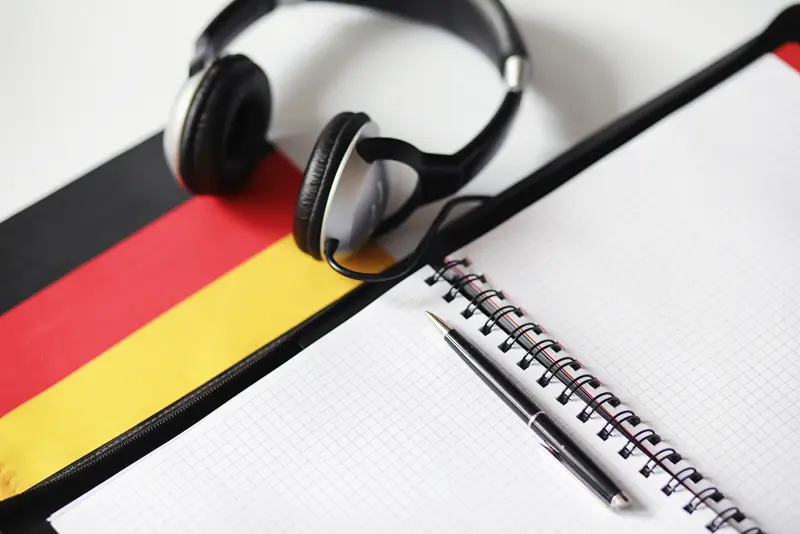 Deutschlandfahne, Kopfh&ouml;rer und aufgeschlagenes Notizbuch