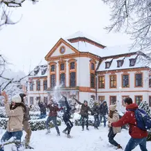Mit KI erstelltes Foto: Studierende machen eine Schneeballschlacht vor der Sommerresidenz