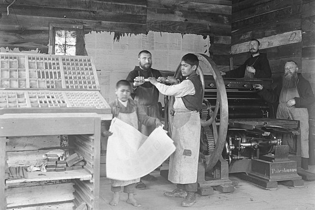 Three Capuchin missionaries in a printing house in Valdivia, in the process of operating a printing press together with their indigenous students. In the foreground, you can see a typesetting box with printing letters. The photograph was taken around 1927. (Photo: University Library Eichstätt-Ingolstadt, shelf number: VA15_S20_015)