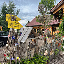 Ein Holzzaun an einem Garten mit Haus im Hintergrund. Auf dem Holz ein Schild mit "Tag der offenen Gartentür" 