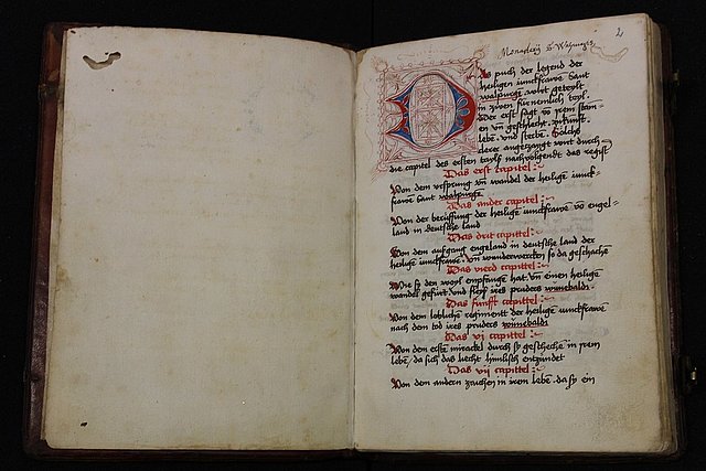 Aufgeschlagene spätmittelalterliche Handschrift, die linke Seite ist leer, auf der rechten Seite ist eine rubrizierte Initiale und Text in schwarzer Tinte