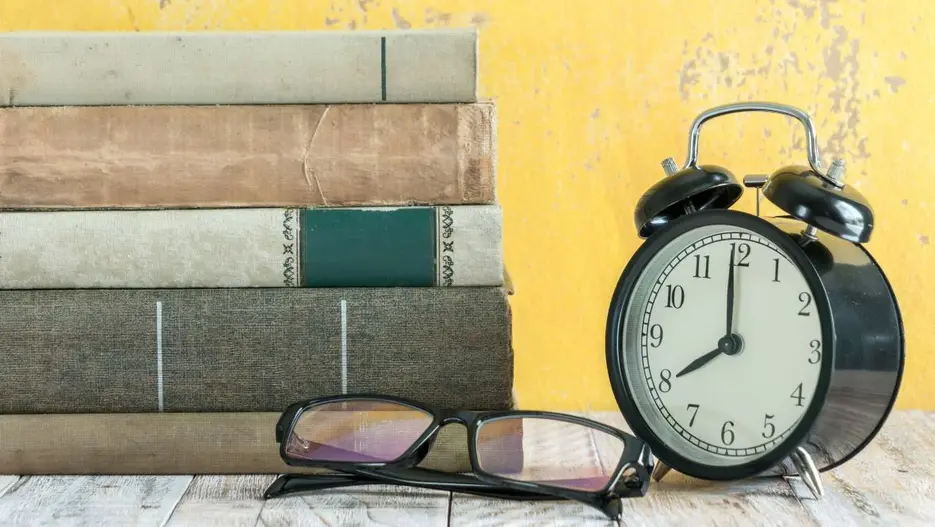 Bücherstapel neben einem Wecker