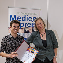 Das Foto zeigt Johannes Hirschlach und Henriette Löwisch. Johannes Hirschlach hält eine Urkunde in der Hand. 