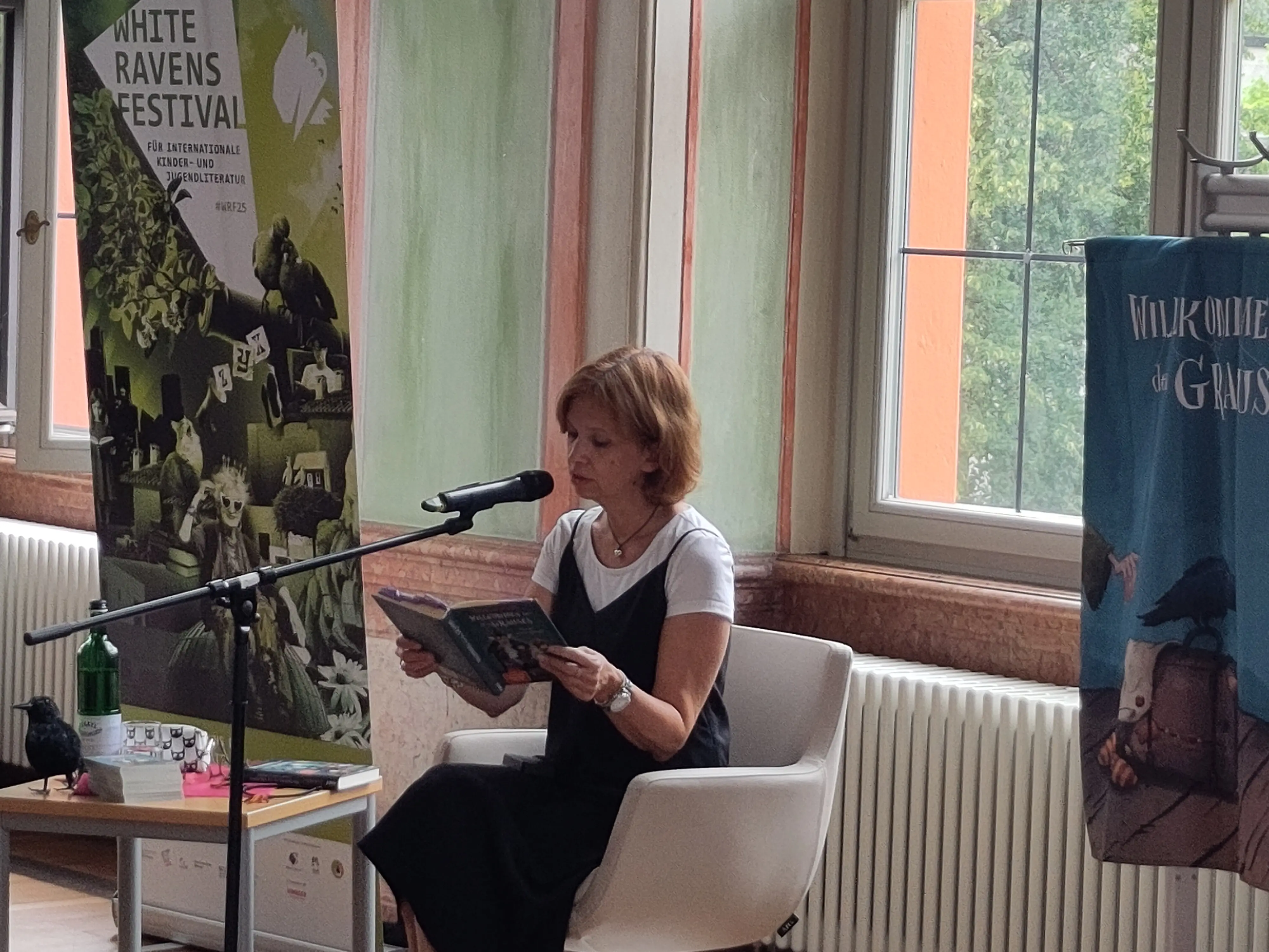 Eine Frau sitzt auf einem Sessel und liest ein Buch.