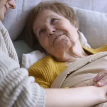 Alte bettl&auml;grige Frau mit pflegender Person