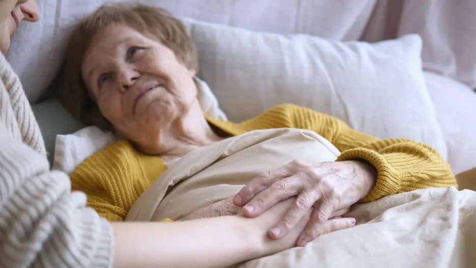 Alte bettl&auml;grige Frau mit pflegender Person