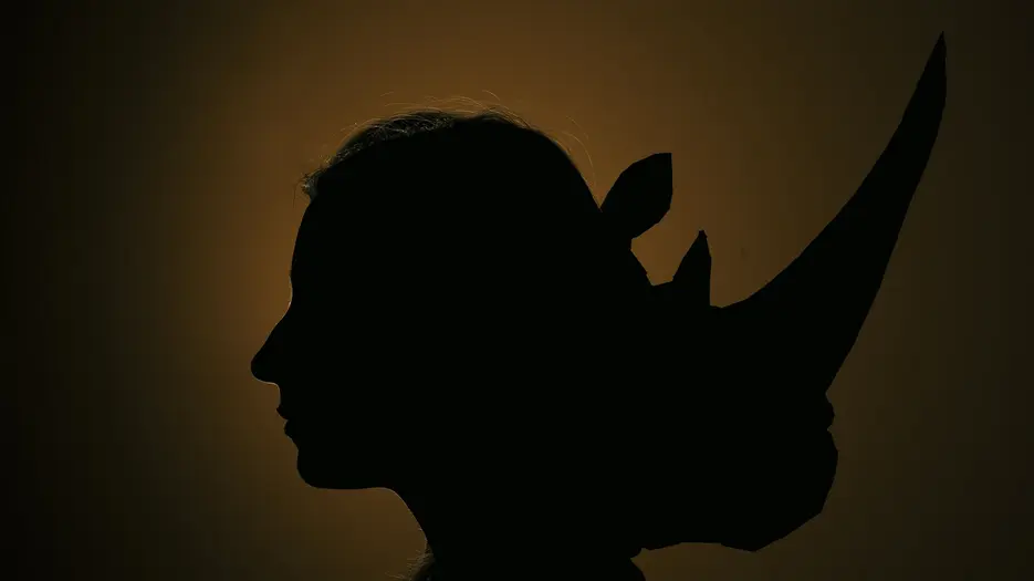 Das Plakat zeigt vor dunklem Hintergrund die Silhouette eines Kopfes mit zwei Gesichten - dem eines Menschen und dem eines Nashorns.