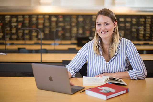 Universitätsbibliothek: Studentin mit Laptop im Lesesaal