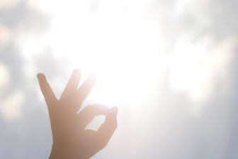 Eine Hand nach oben gestreckt, im Hintergrund Sonnenlicht