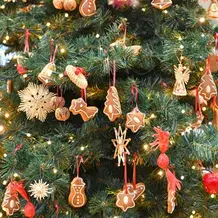 Ein Tannenbaum geschmückt mit Lebkuchen, Lichterkette und Strohengeln.