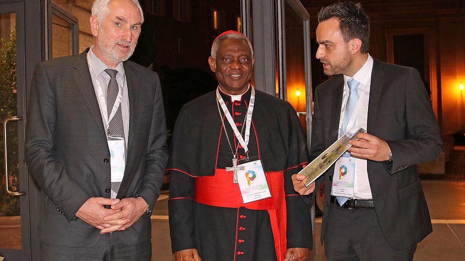 Head of the Laudato Si’ project, Prof. Dr. Ulrich Bartosch (left) and project team member Christian Meier presented Cardinal of the Roman Curia Peter Turkson, who had invited the guests to the conference in his function as prefect of the Vatican Dicastery for Promoting Integral Human Development, with an overview of their project activities. (Photo: Meier/upd)