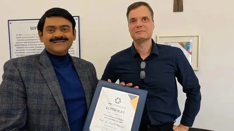 Prof. Dr. Shashi Matta h&auml;lt die Urkunde des WFI Highlight in den H&auml;nden, neben ihm Dekan Prof. Dr. Thomas M&auml;hlmann.