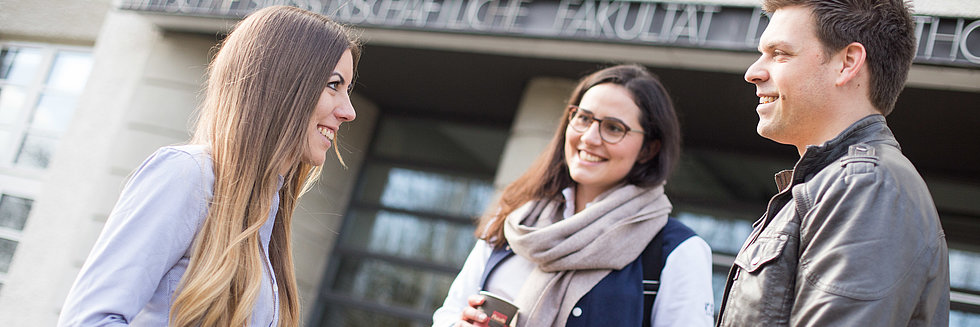 Drei Studierende mit Kaffee vor der WFI